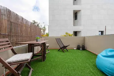 a patio with a table and chairs and green grass at By the Sea III Lido - com piscina in Funchal