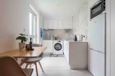a white kitchen with a table and a refrigerator at By the Sea III Lido - com piscina in Funchal