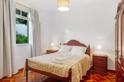 a bedroom with a bed with two lamps and a window at Casal Do Farrobo in Funchal