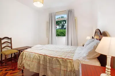 a bedroom with a bed and a table and a window at Casal Do Farrobo in Funchal