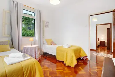 a bedroom with two beds with yellow sheets and a mirror at Casal Do Farrobo in Funchal