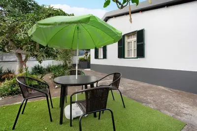 a table and two chairs with a green umbrella at Casal Do Farrobo in Funchal