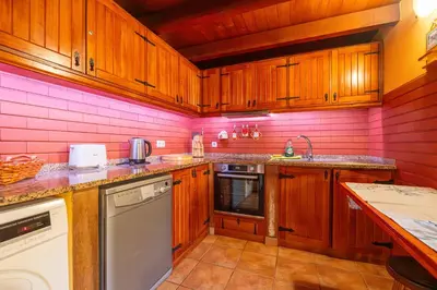 a kitchen with pink walls and wooden cabinets at Villa Fontes 5 in Ponta Delgada