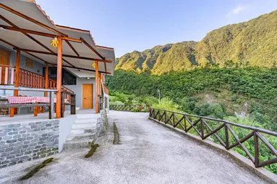 a building with a fence next to a mountain at Villa Fontes 7 in Ponta Delgada
