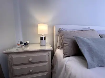 a bed with a night stand with a lamp on it at By the Sea - Apartamento acolhedor e relaxante. in Caniço