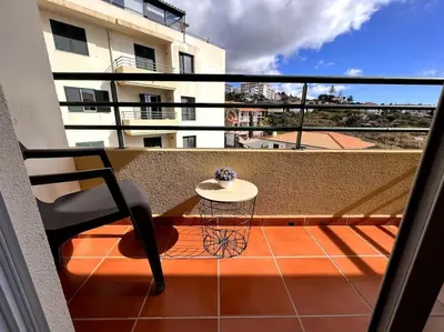 a balcony with a table and a chair on a balcony at By the Sea - Apartamento acolhedor e relaxante. in Caniço
