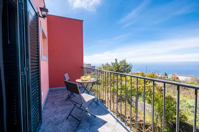 a balcony with a table and a view of the ocean at The Red Nest by GALMI in Arco da Calheta