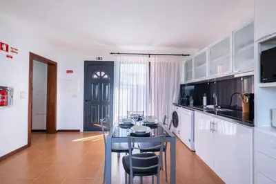 a kitchen with a table and chairs in a room at The Red Nest by GALMI in Arco da Calheta