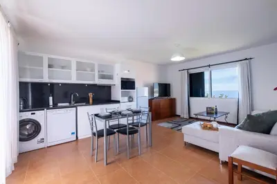 a kitchen and living room with a couch and a table at The Red Nest by GALMI in Arco da Calheta