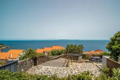 a house with a fence and a stone patio at Madeirense Villa in Santa Cruz in Santa Cruz