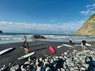 a group of people walking on a beach with surfboards at Sea Breeze Boutique House in Porto da Cruz