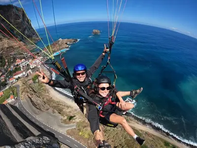 two people are riding a parachute over the ocean at Sea Breeze Boutique House in Porto da Cruz