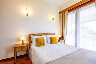 a bedroom with a bed with yellow pillows and a window at Vila Gama Apartaments in Machico