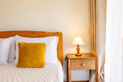 a bed with a yellow pillow and a lamp on a night stand at Vila Gama Apartaments in Machico