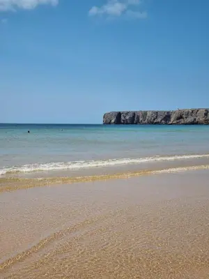 a beach with the ocean and rocks in the background at Bella Sunset Holidays - 3 min da Praia da Mareta in Sagres