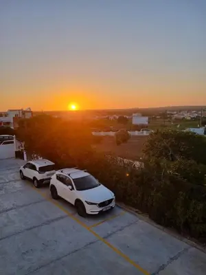 two cars parked in a parking lot with the sunset in the background at Bella Sunset Holidays - 3 min da Praia da Mareta in Sagres