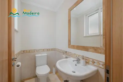 a bathroom with a sink and a toilet and a mirror at OurMadeira - Palheiro Eagle in Funchal