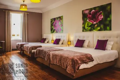 a hotel room with three beds and a painting on the wall at Santa Maria Hostel in Funchal