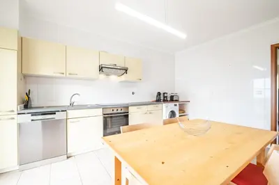 a kitchen with white cabinets and a wooden table at Bela Vista Valley in Calheta