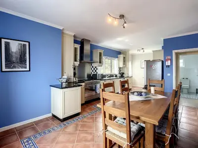 a kitchen with blue walls and a wooden table and chairs at Vinhaticos Villa by Atlantic Holiday in Porto Moniz