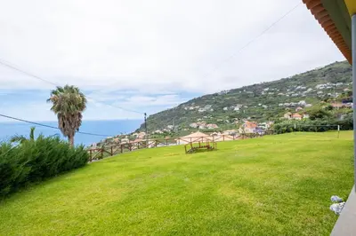 a green field with a picnic table on a hill at Shell House by GALMI in Arco da Calheta
