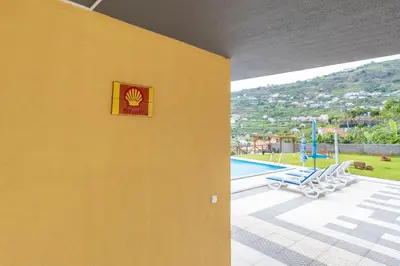 a yellow wall with a sign on it next to a pool at Shell House by GALMI in Arco da Calheta