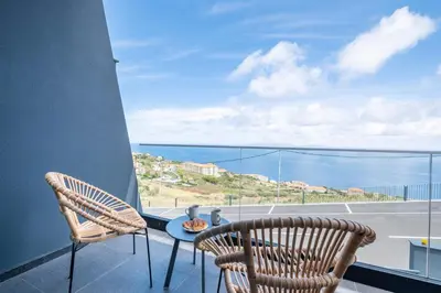 a balcony with two chairs and a table with a view of the ocean at Villa Bela Horizonte by GALMI in Caniço