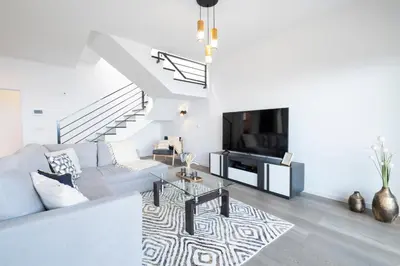 a white living room with a couch and a tv at Villa Bela Horizonte by GALMI in Caniço