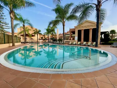 a large swimming pool with palm trees and a building at E&M Apartment Luz in Luz