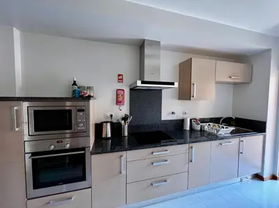 a kitchen with stainless steel appliances and wooden cabinets at E&M Apartment Luz in Luz