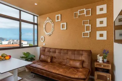 a living room with a brown leather couch and a table at SUPER Central - Cork in Funchal