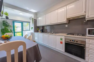 a kitchen with white cabinets and a table and a microwave at SUPER Anadia - Olive in Funchal