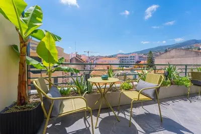 a patio with chairs and a table on a balcony at SUPER Anadia - Olive in Funchal