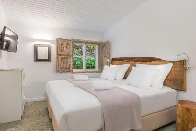 a bedroom with a large white bed and a window at Rabaçal Nature Spot Cottage in Estreito da Calheta