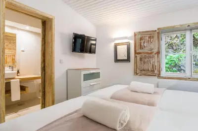 two beds in a room with a sink and a mirror at Rabaçal Nature Spot Cottage in Estreito da Calheta