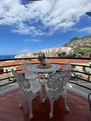 a table and chairs on a balcony with a fountain at Residência Azevedo in Câmara de Lobos
