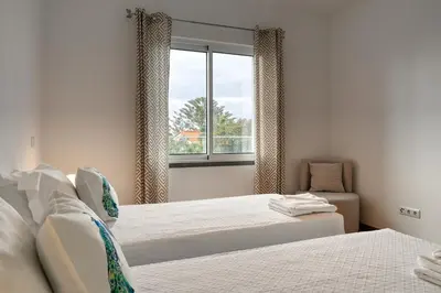 a bedroom with two beds and a window at Tamariz Sea View, a Home in Madeira in Caniço