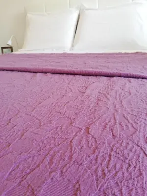 a bed with a purple blanket and white pillows at FXapartment1 in Funchal