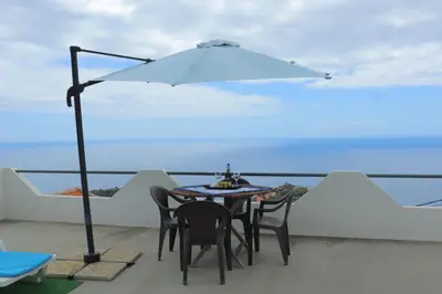 a balcony with chairs and a table and a window at Fifty`s House 1 By Sam Houses in Ribeira Brava