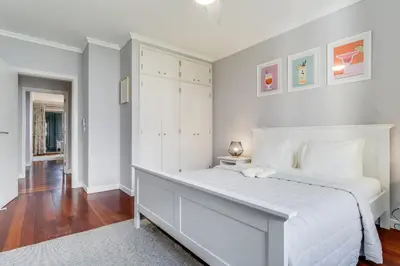 a white bedroom with a large white bed and wooden floors at Apartament Falesia Paradise by Holiday Rental Madeira in Funchal
