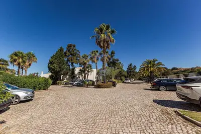 a cobblestone parking lot with palm trees and cars at Vilamos in Lagos by Algarve Golden Properties in Lagos