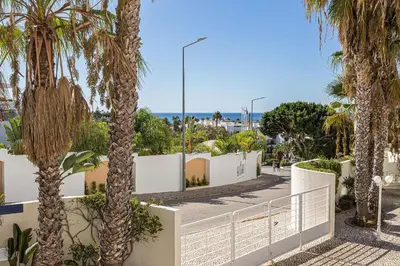 a street with palm trees and a white fence at Vilamos in Lagos by Algarve Golden Properties in Lagos