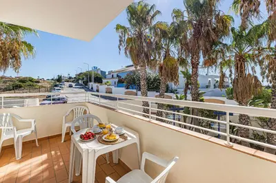 a balcony with a table and chairs and palm trees at Vilamos in Lagos by Algarve Golden Properties in Lagos