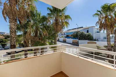 a balcony with palm trees and a building at Vilamos in Lagos by Algarve Golden Properties in Lagos