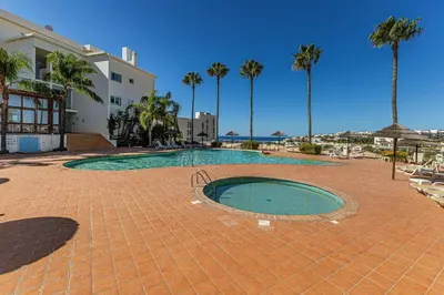 a swimming pool with palm trees and a building at Vilamos in Lagos by Algarve Golden Properties in Lagos