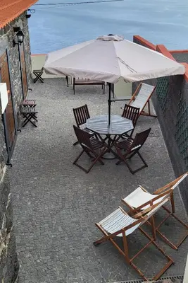 a table and chairs with an umbrella on a patio at Refúgio do Santa in Calheta