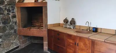 a kitchen with a stone fireplace and a sink at Refúgio do Santa in Calheta