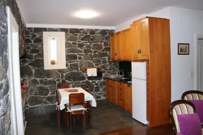 a kitchen with a table and a stone wall at Refúgio do Santa in Calheta