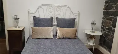 a bed with a white headboard and pillows at Refúgio do Santa in Calheta