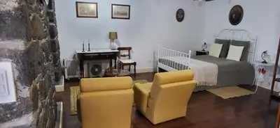 a bedroom with a bed and two yellow chairs at Refúgio do Santa in Calheta
